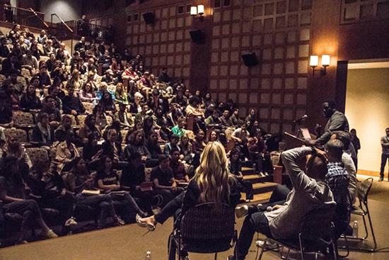 audience as seen from behind people seated on the stage