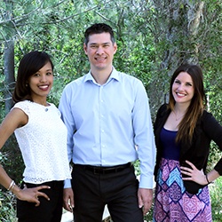 Two female and one male student pose in front of trees