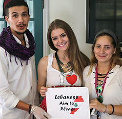 Three students hold a sign that reads Lebanese Aim to Please