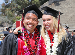 Two students in caps and gowns celebrate graduation