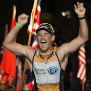 runner crosses the finish line and raises his arms in triumph