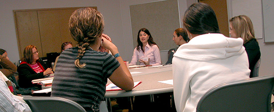 people sitting in circle around table discussing mental health counseling